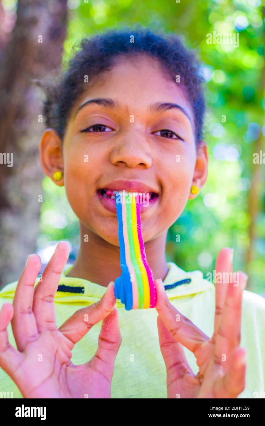 happy little girl smiles as she eats a soft licorice of all colors