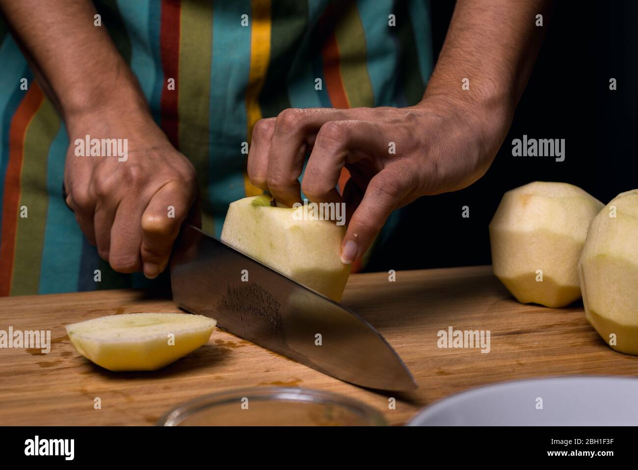Working in the kitchen. Detail of hands cutting apple into pieces ...