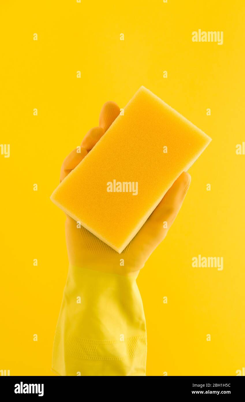 Hand wearing a yellow rubber glove holding a cleaning sponge Stock ...