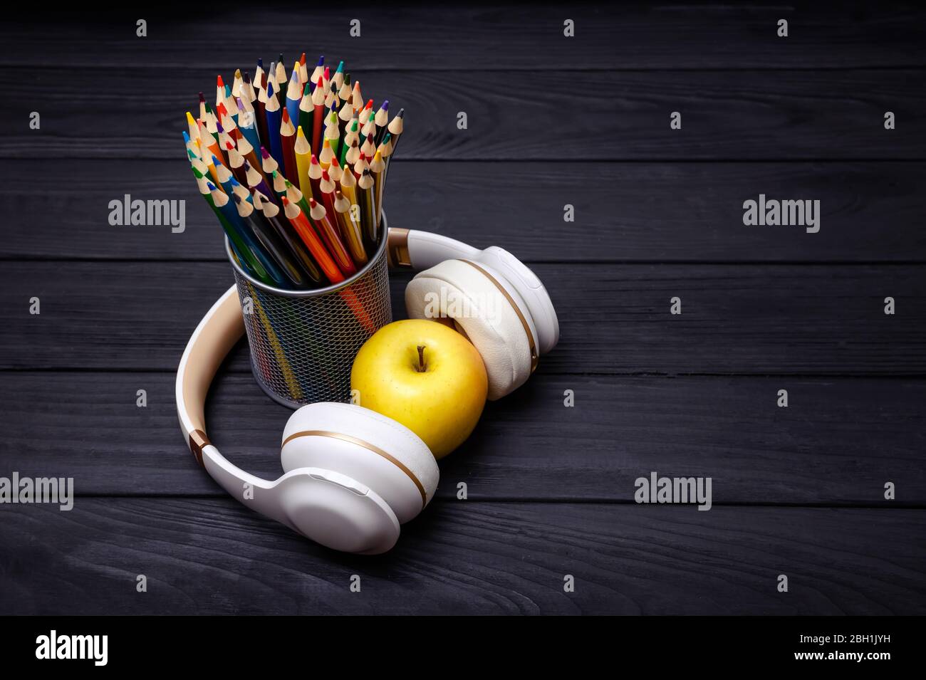 Colorful pencils and headphones on black wooden background. Workplace Stock Photo