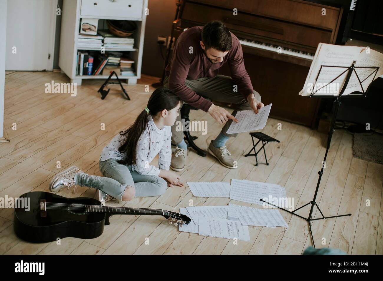 Cute little girl playing guitar with her music teacher in the rustic