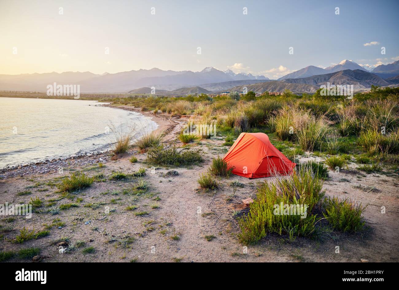 Orange tent on the shore of Issyk Kul mountain lake in Kyrgyzstan Stock Photo