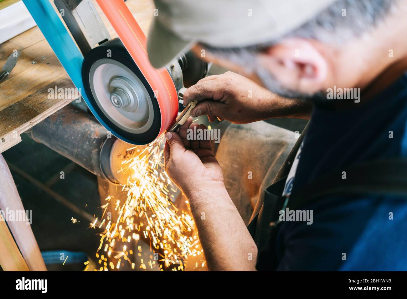 Craftsman making knives in his workshop sharpening the blade Stock Photo