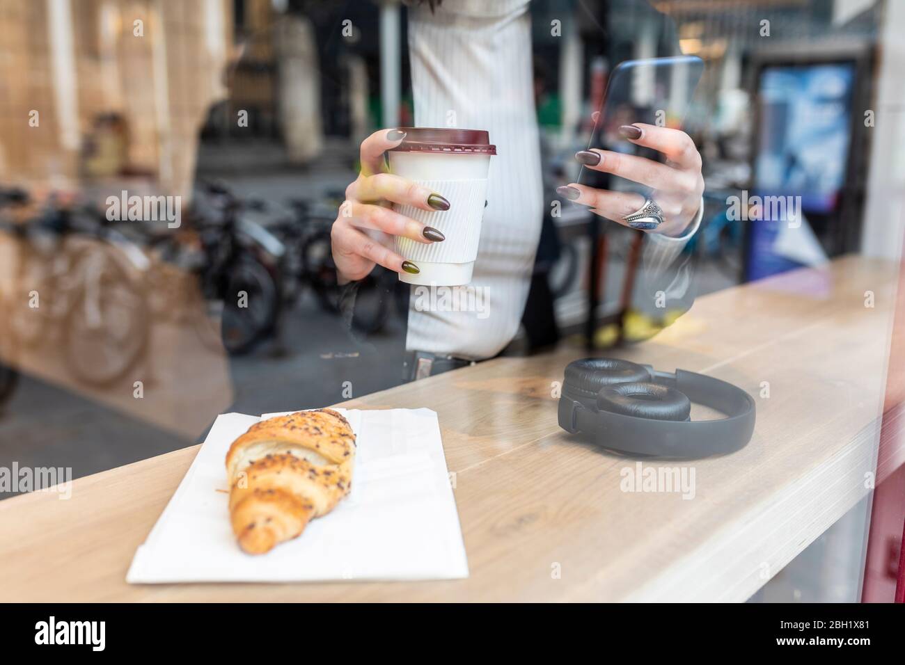 Close-up of businesswoman having a coffee break and using mobile phone at a cafe in the city Stock Photo