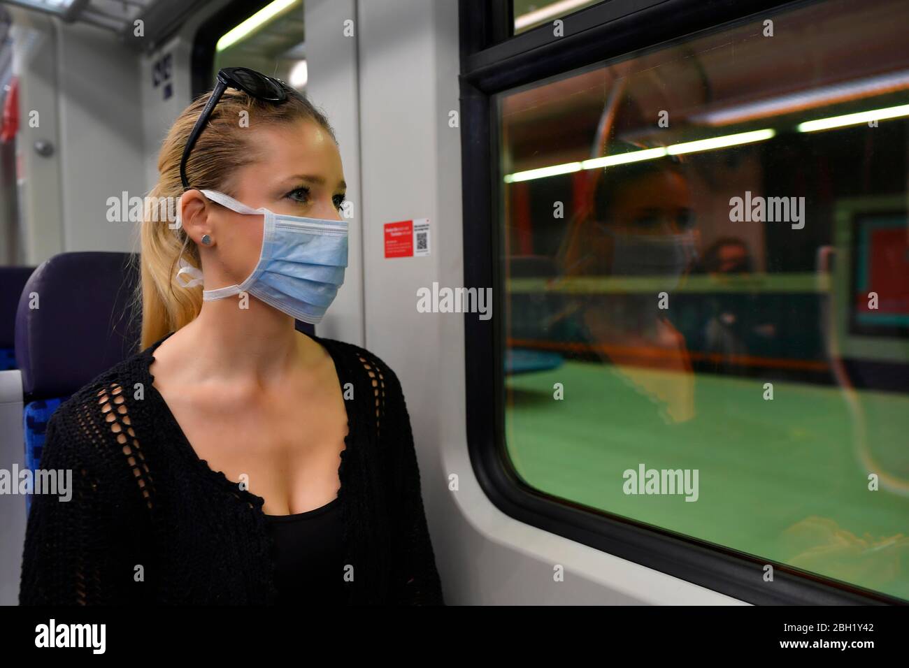 Woman with a respirator mask, sitting in train, reflected in S-Bahn, corona crisis, Stuttgart, Baden-Wuerttemberg, Germany Stock Photo