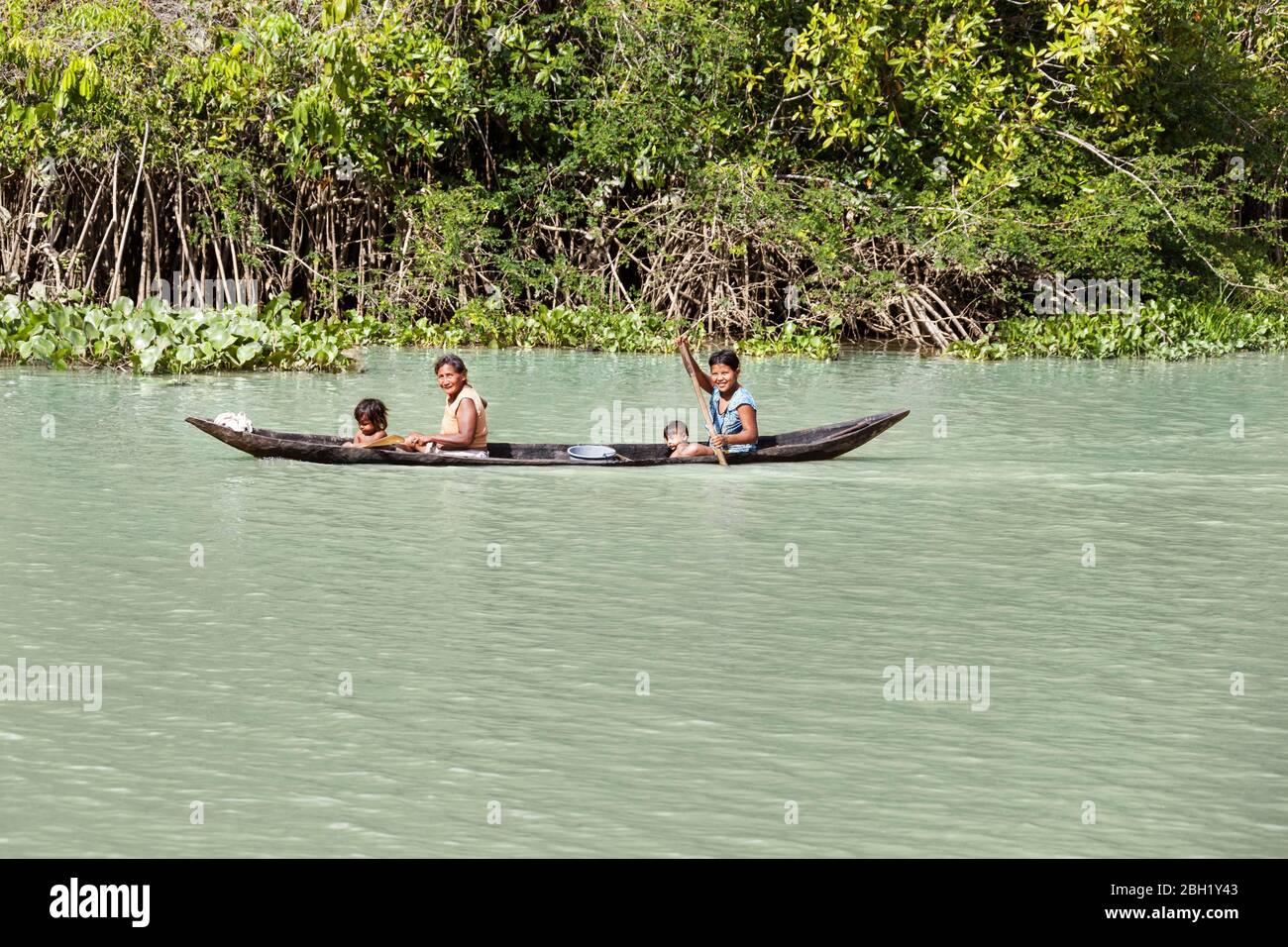 Native woman with small children rowing in a dugout boat in the Orinoco Delta, Warao tribe, indigenous people, Venezuela Stock Photo