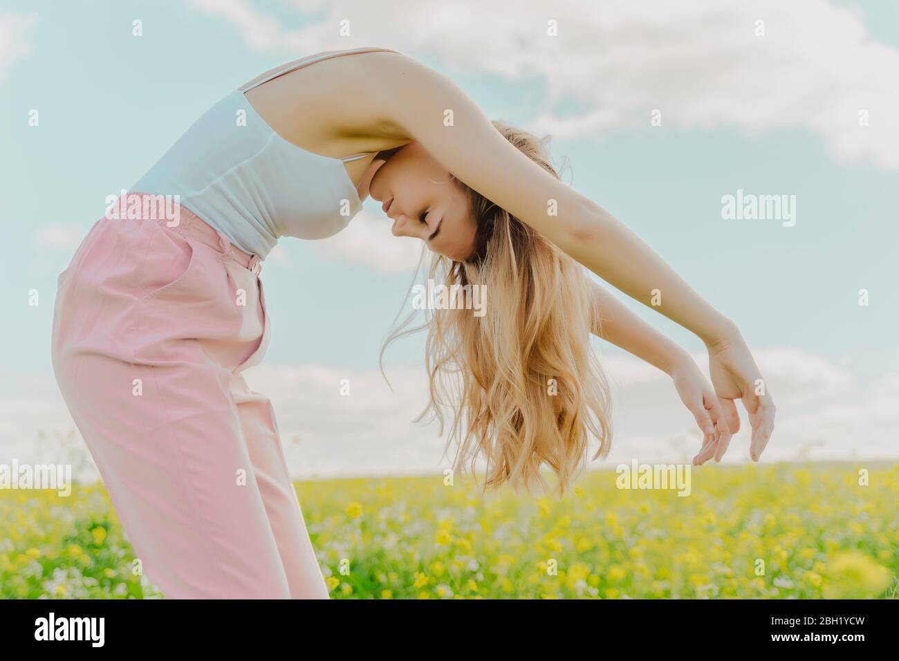 Young woman bending over in a flower meadow in spring Stock Photo Alamy