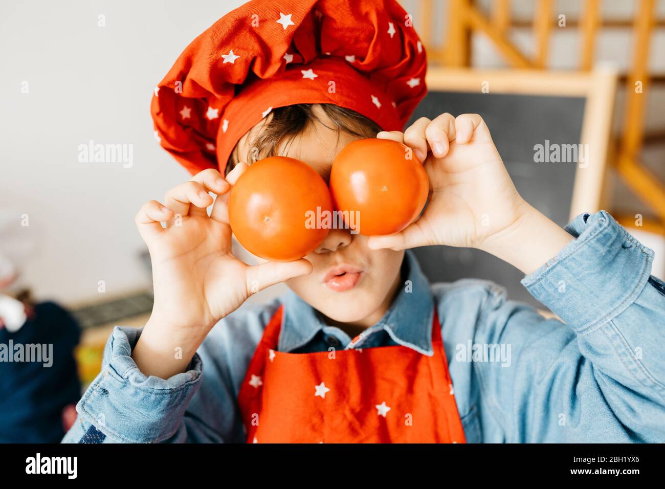 Playful boy covering his eyes with tomatoes in kitchen Stock Photo - Alamy