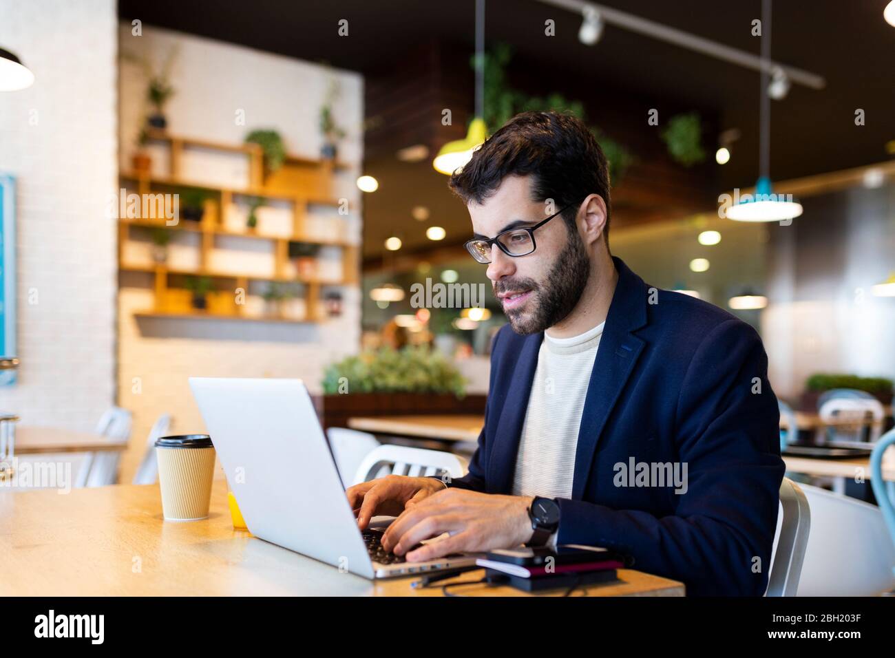 Portrait of businessman working on laptop in a coffee shop Stock Photo