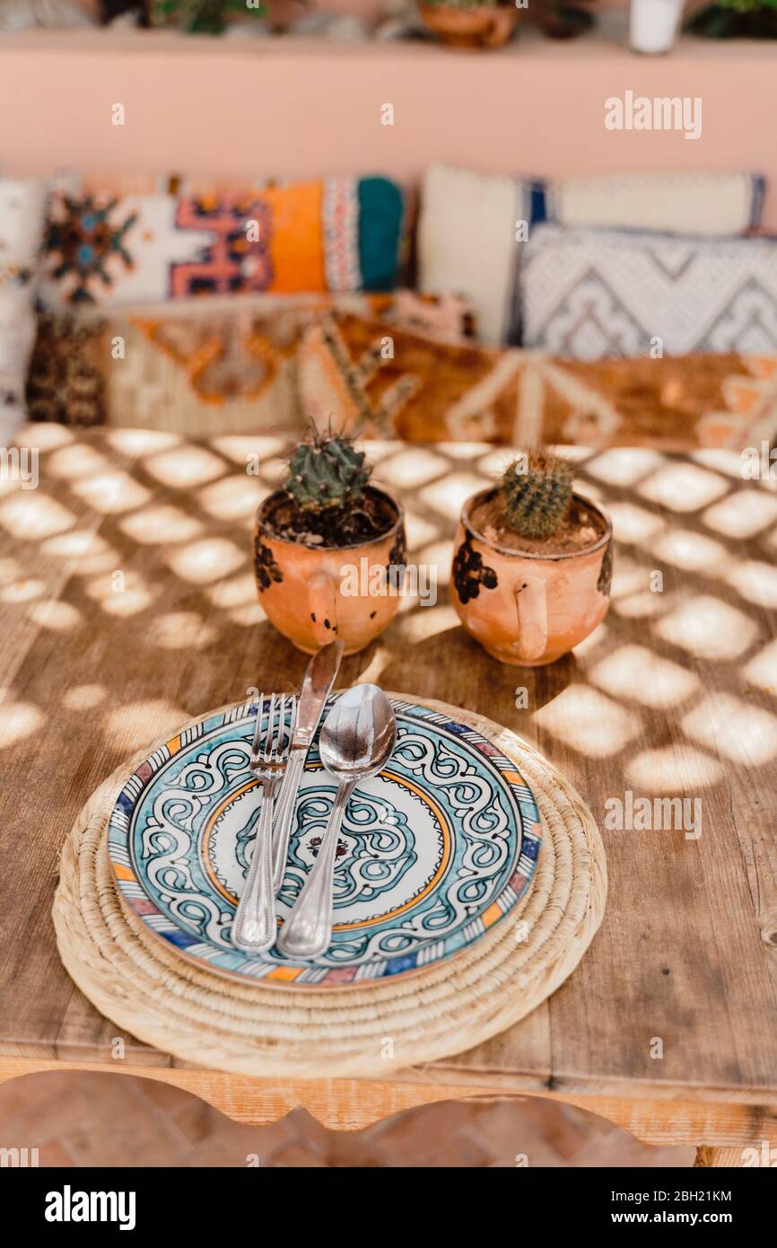 Morocco, Table with two potted cacti and cutlery lying on ornate plate Stock Photo