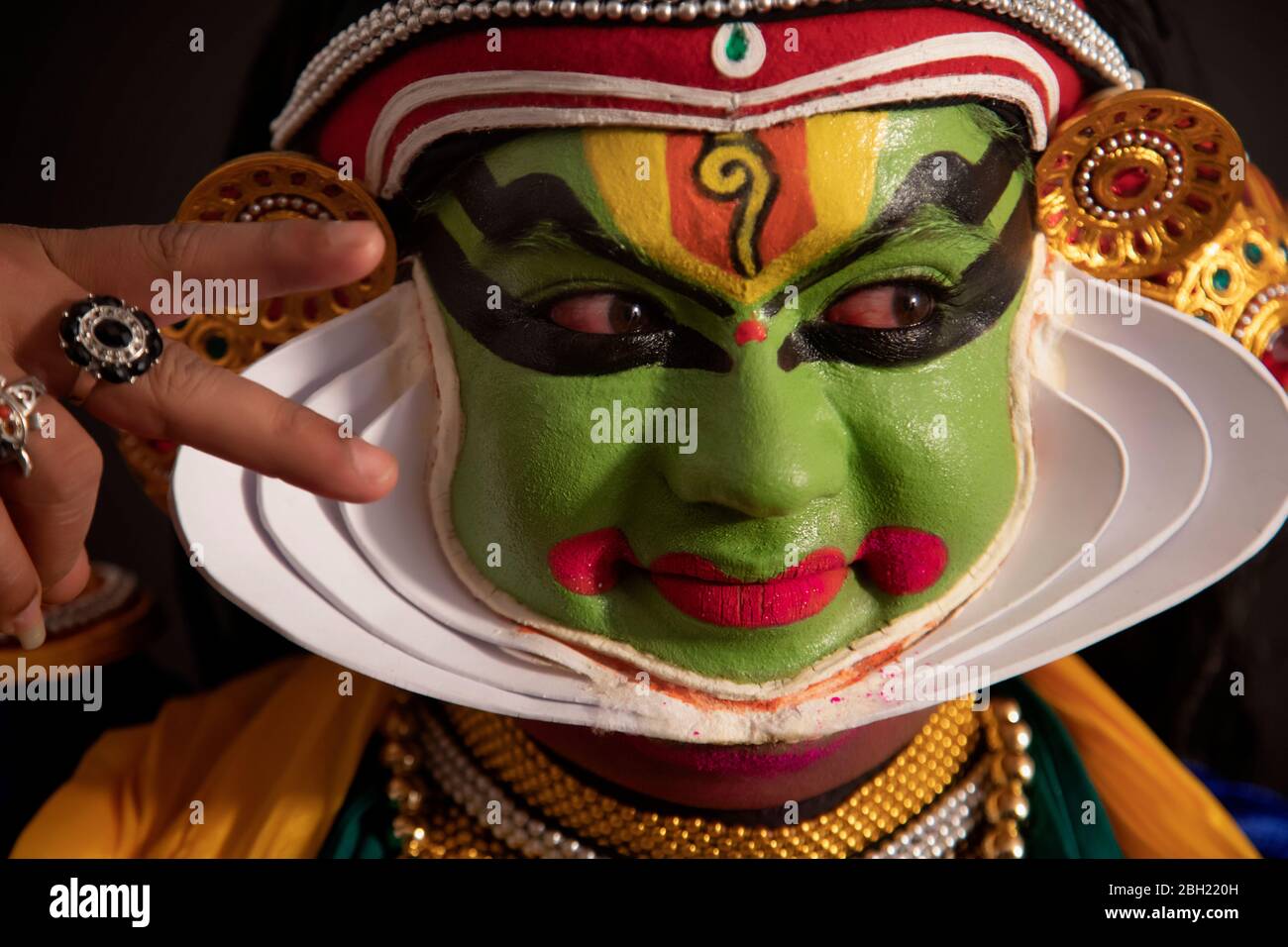 Kathakali dancer giving eye expressions with a smile on his face during