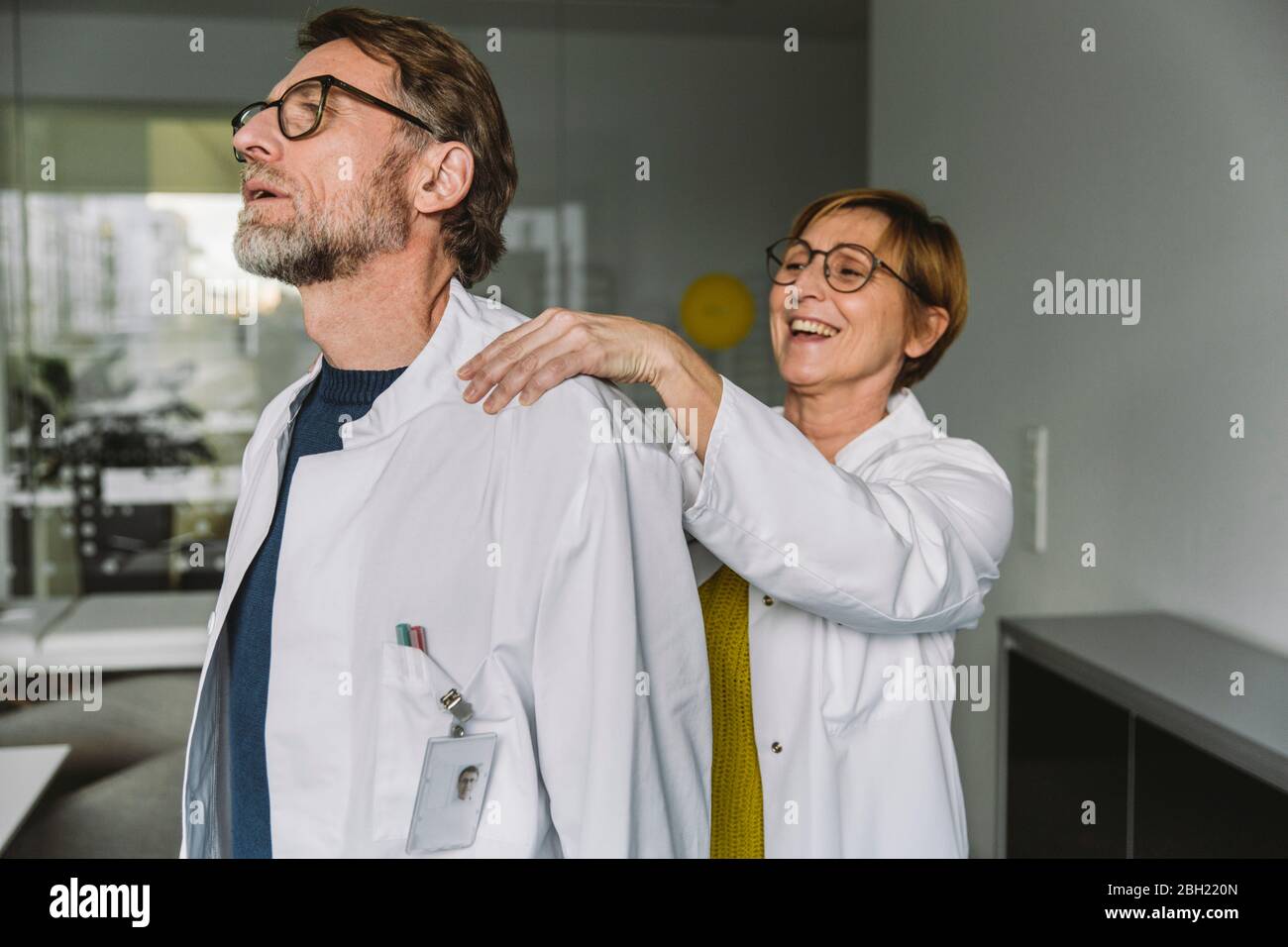 Doctor massaging shoulder of a colleague Stock Photo