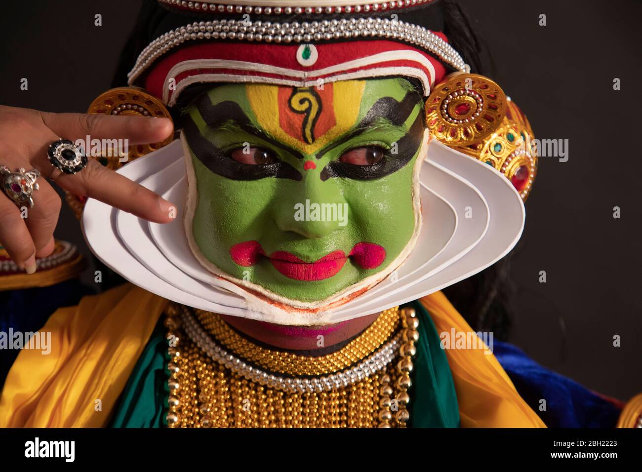 Kathakali dancer giving eye expressions with a smile on his face during
