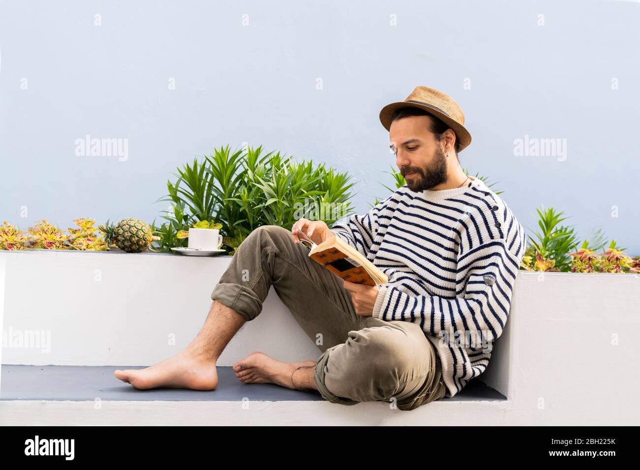 Man sitting on balcony reading a book Stock Photo