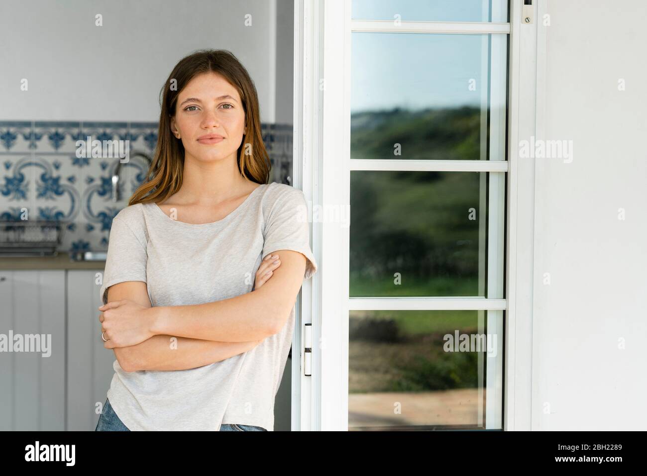 Portrait of attractive young woman standing in the door at home Stock ...