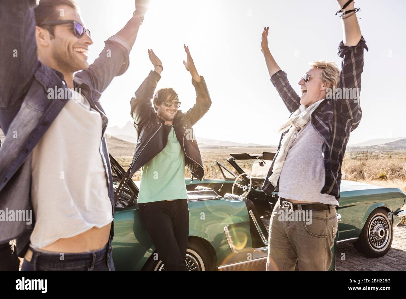 Happy friends at convertible car on a road trip Stock Photo - Alamy