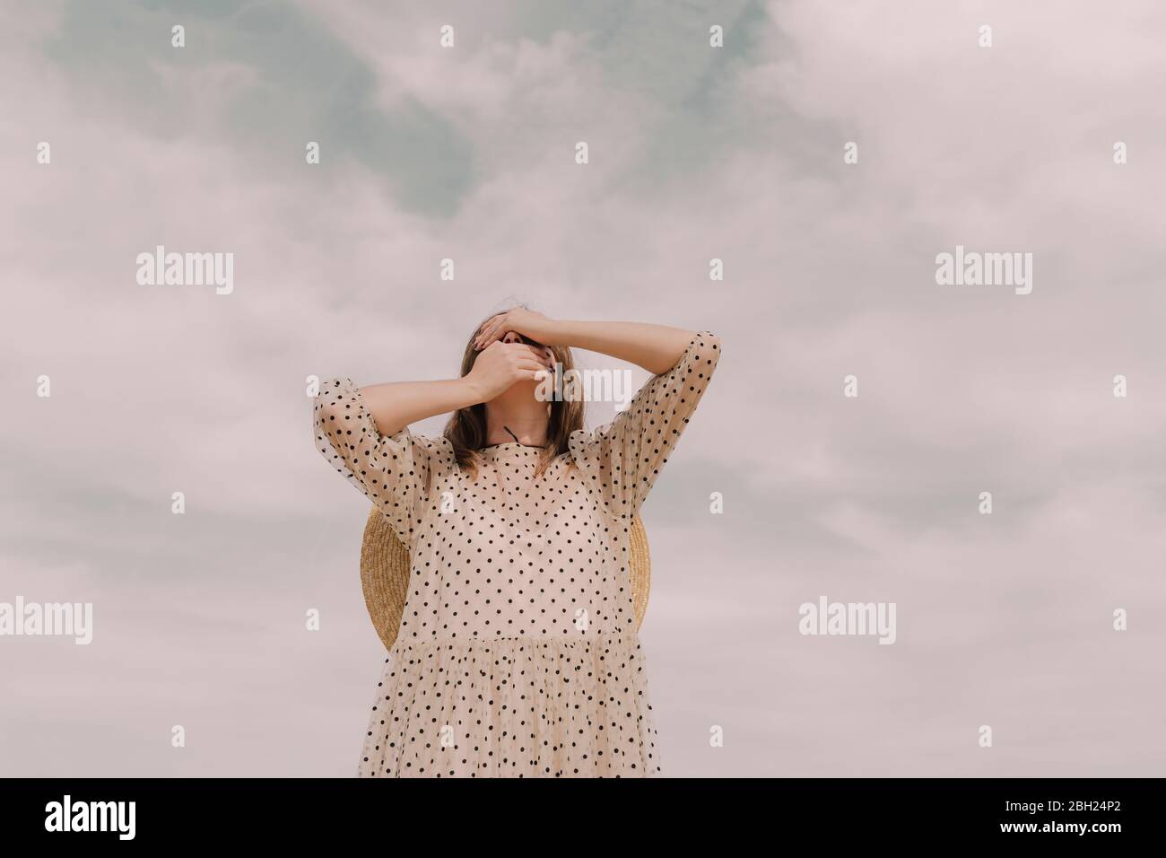 Woman in vintage dress covering her eyes and mouth Stock Photo