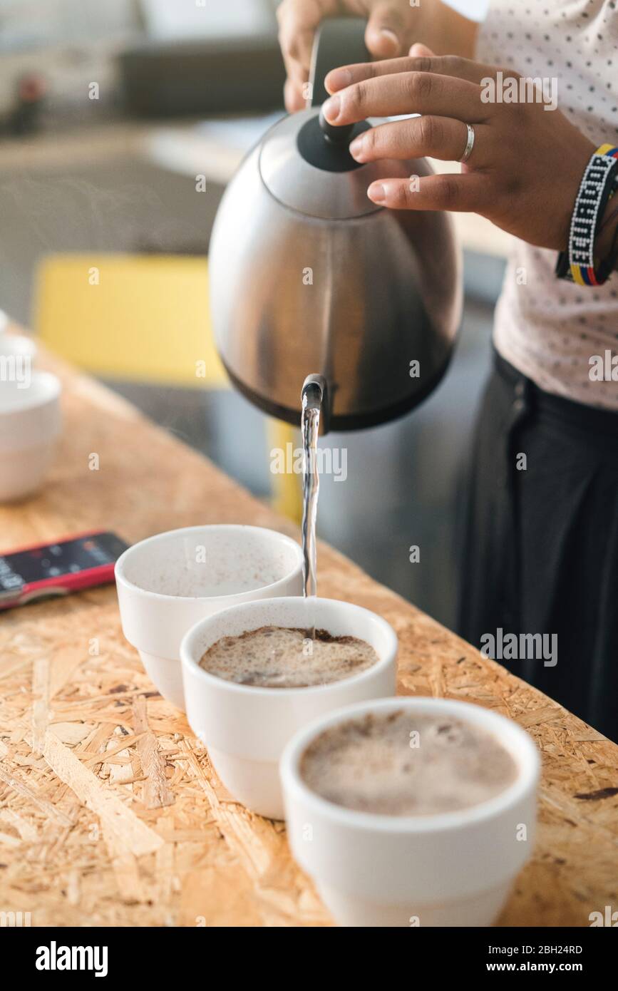 Closeup of woman working in a coffee roastery pouring hot water into