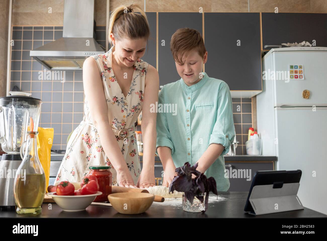 Mother and son kneeling dough together in the kitchen Stock Photo
