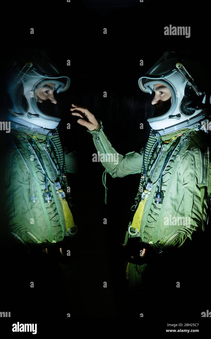 Young spaceman touching his reflection in the dark Stock Photo