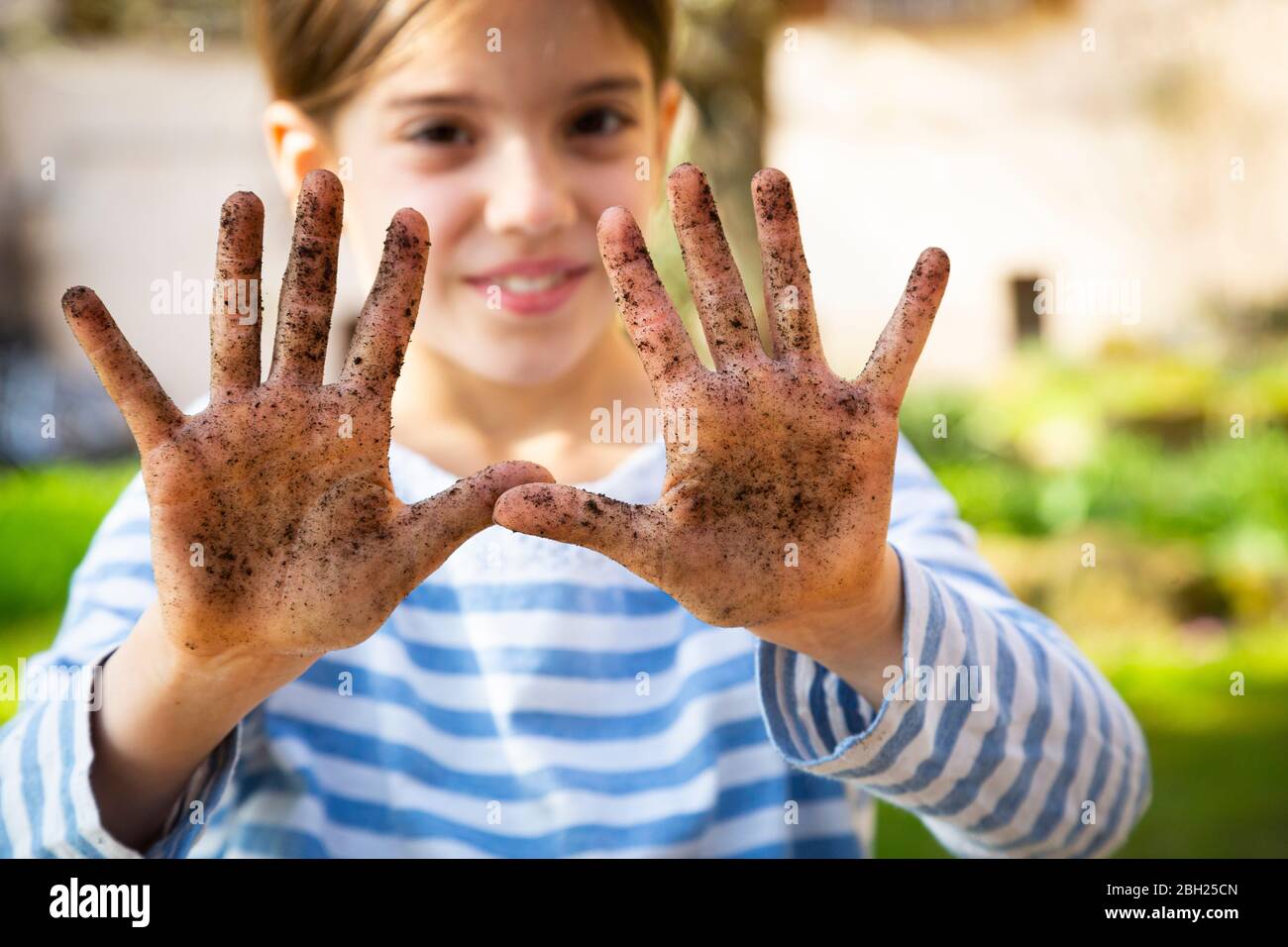 Portrait of smiling girl showing her dirty hands Stock Photo