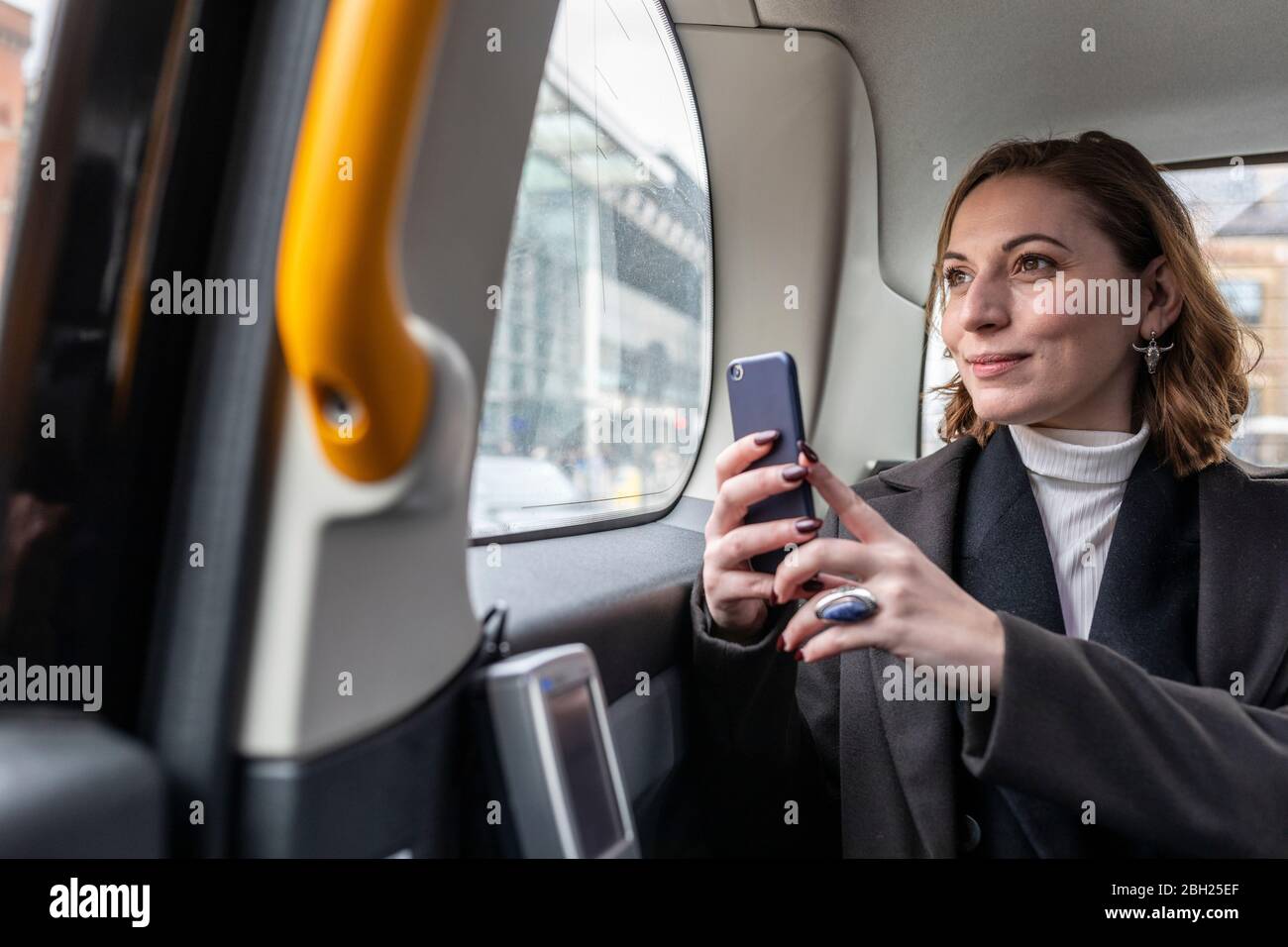 Businesswoman in the rear of a taxi looking out of the window, London, UK Stock Photo