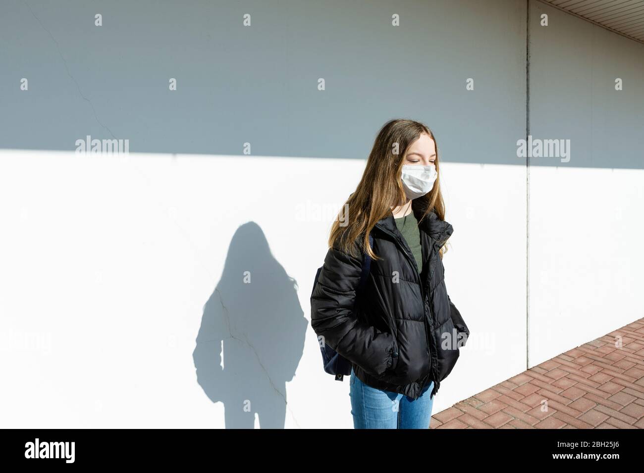 Girl with mask standing in front of a wall Stock Photo