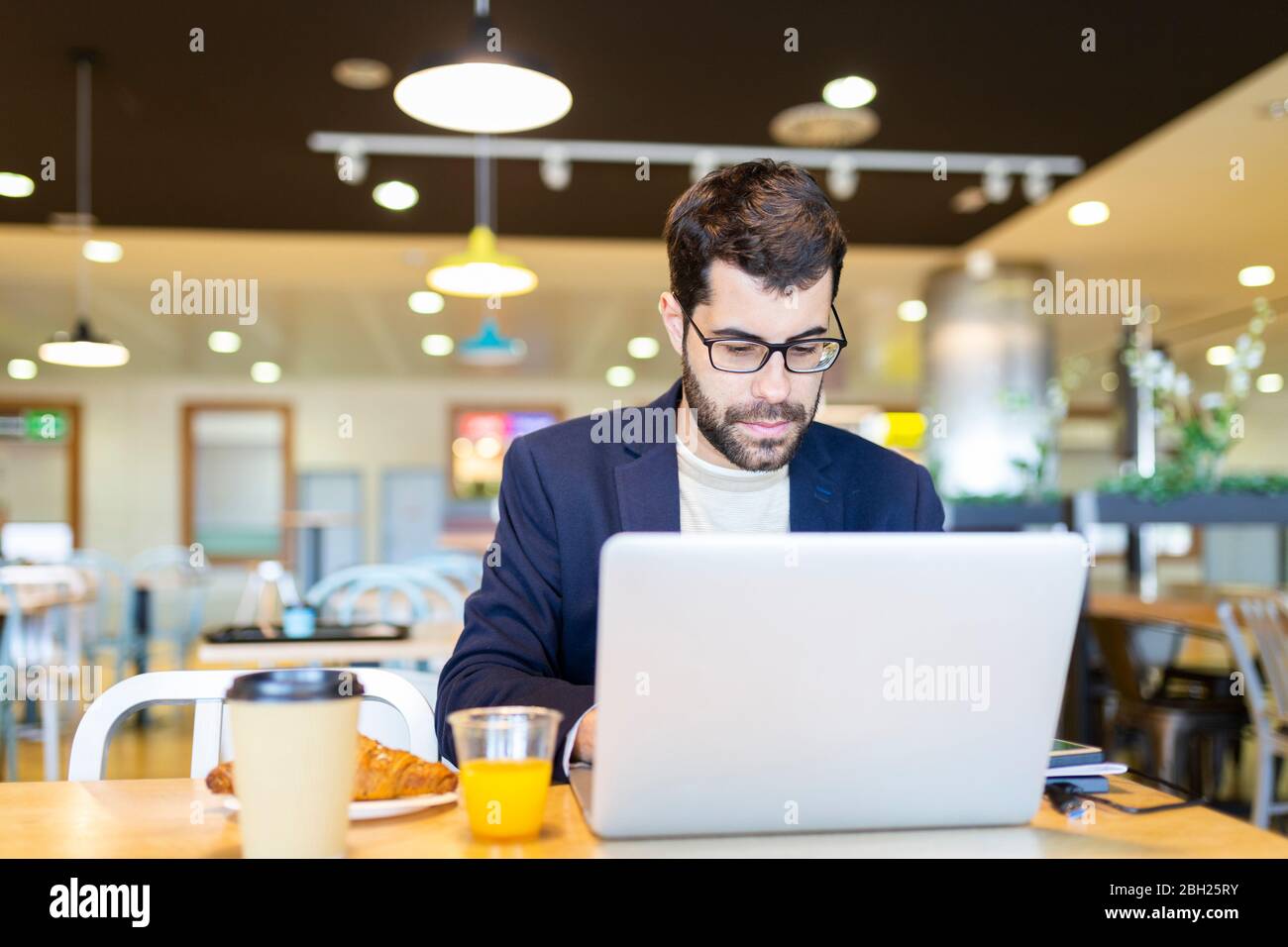 Portrait of bearded businessman working on laptop in a coffee shop Stock Photo