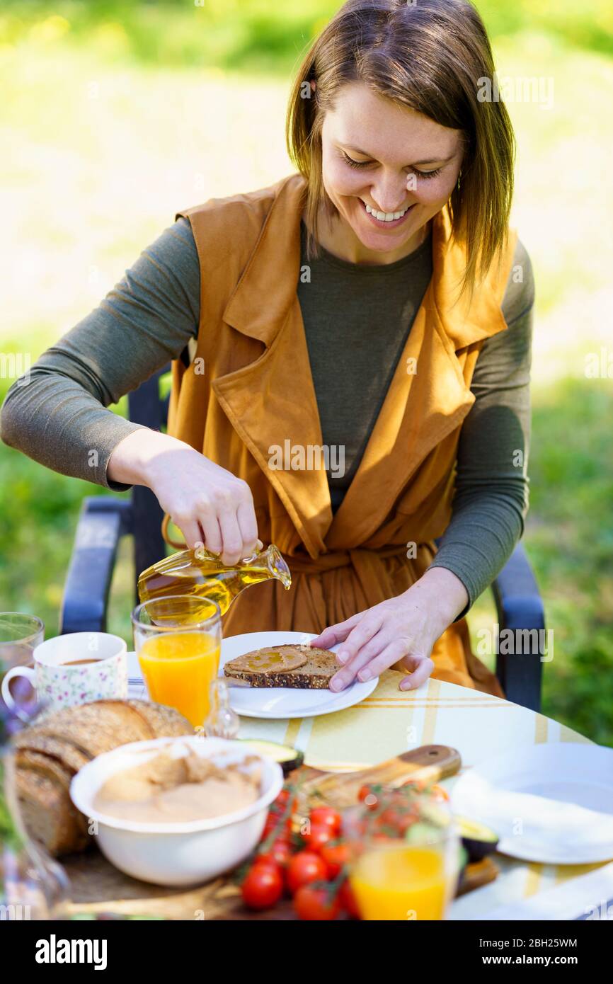 Woman pouring olive oil on bread Stock Photo
