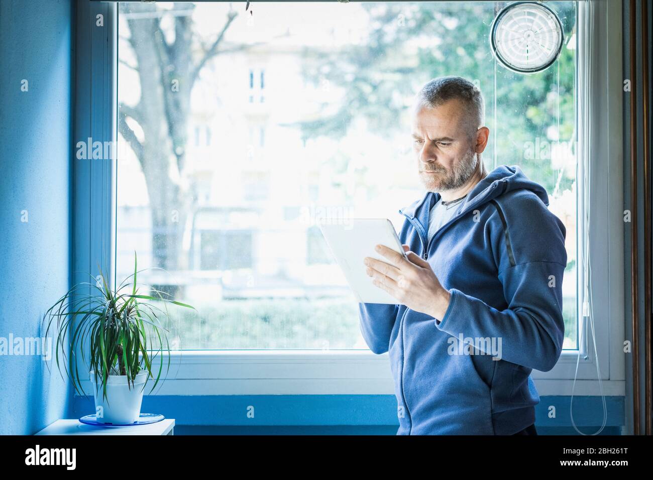 Man using digital tablet near window at home Stock Photo