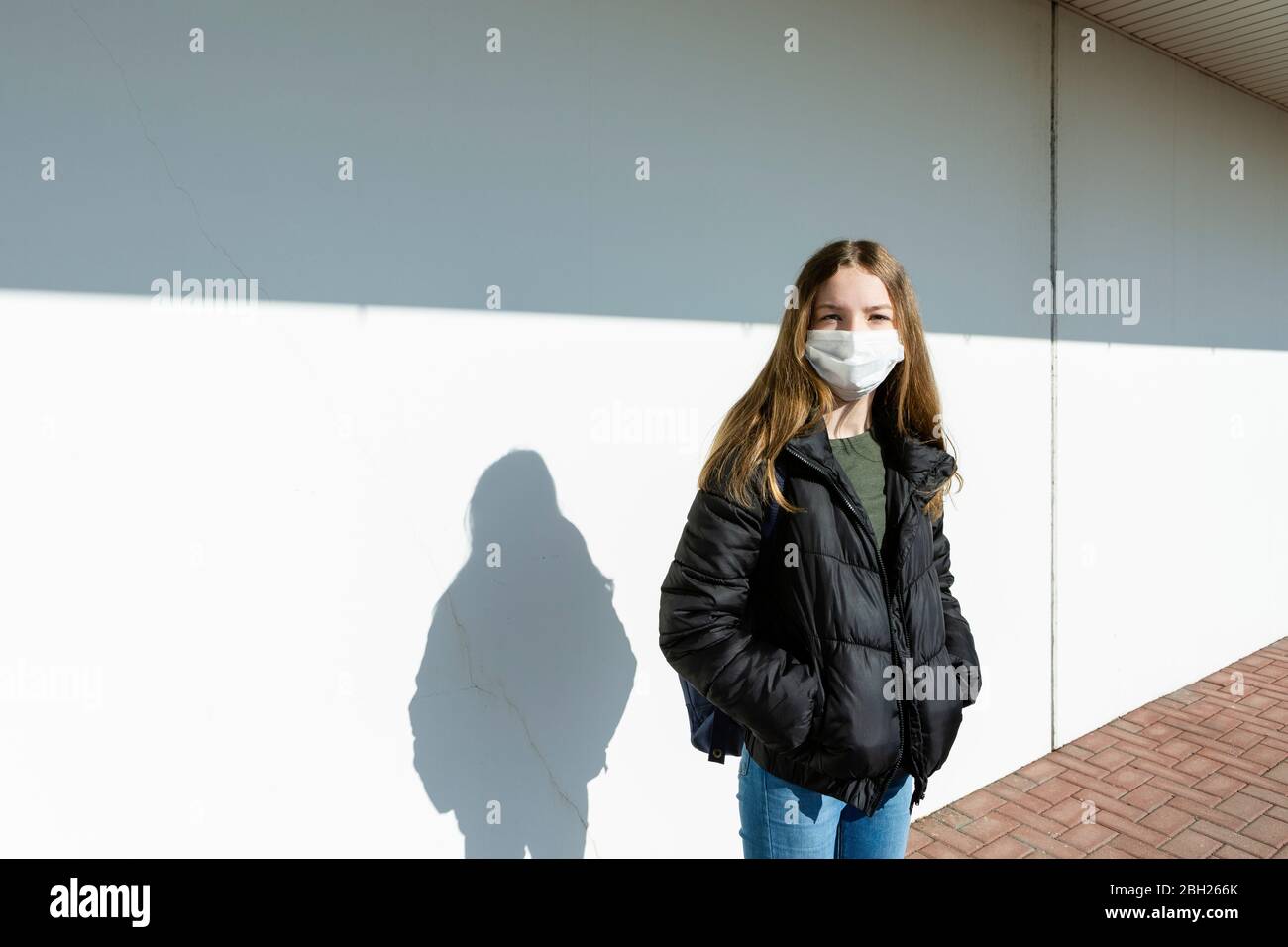 Girl with mask standing in front of a white wall Stock Photo
