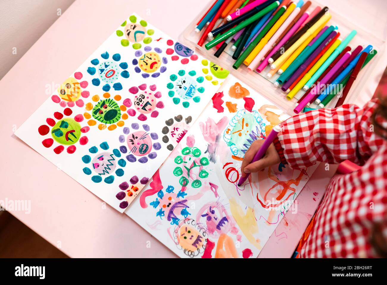 Little girl drawing  ugly viruses with color markers at home Stock Photo