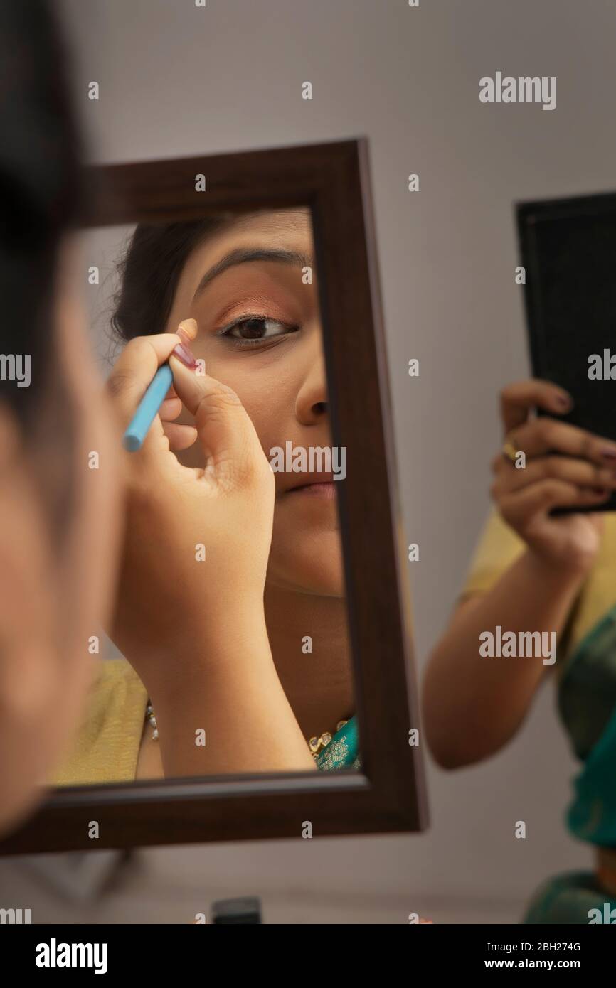 Kathak dancer applying makeup on her face. Stock Photo