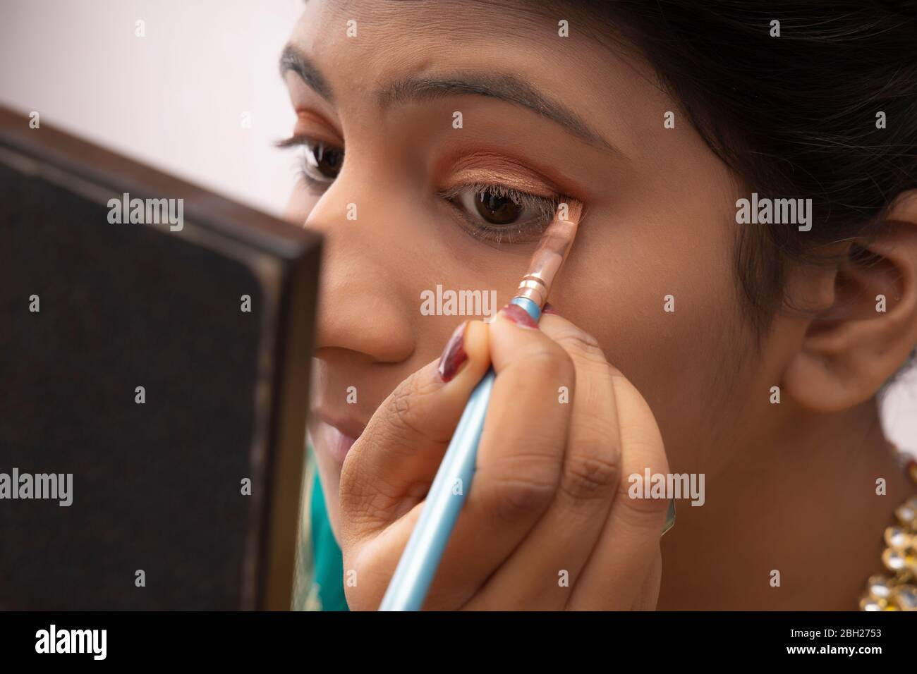 Kathak dancer applying makeup on her face. Stock Photo