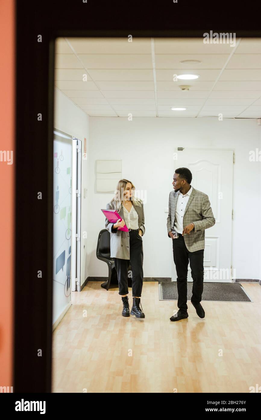 Colleagues walking and talking in office Stock Photo