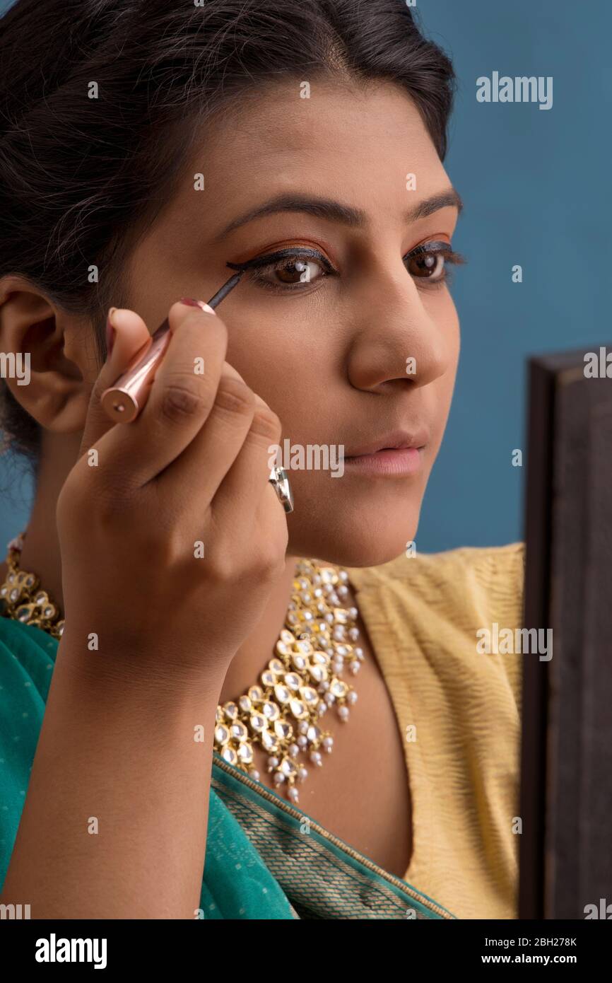 Kathak dancer applying eyeliner on her eyes. Stock Photo
