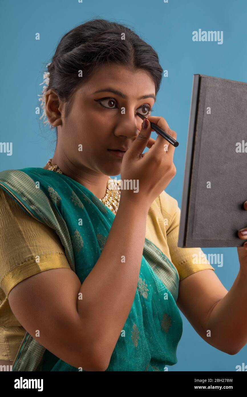 Kathak dancer applying eyeliner on her eyes. Stock Photo