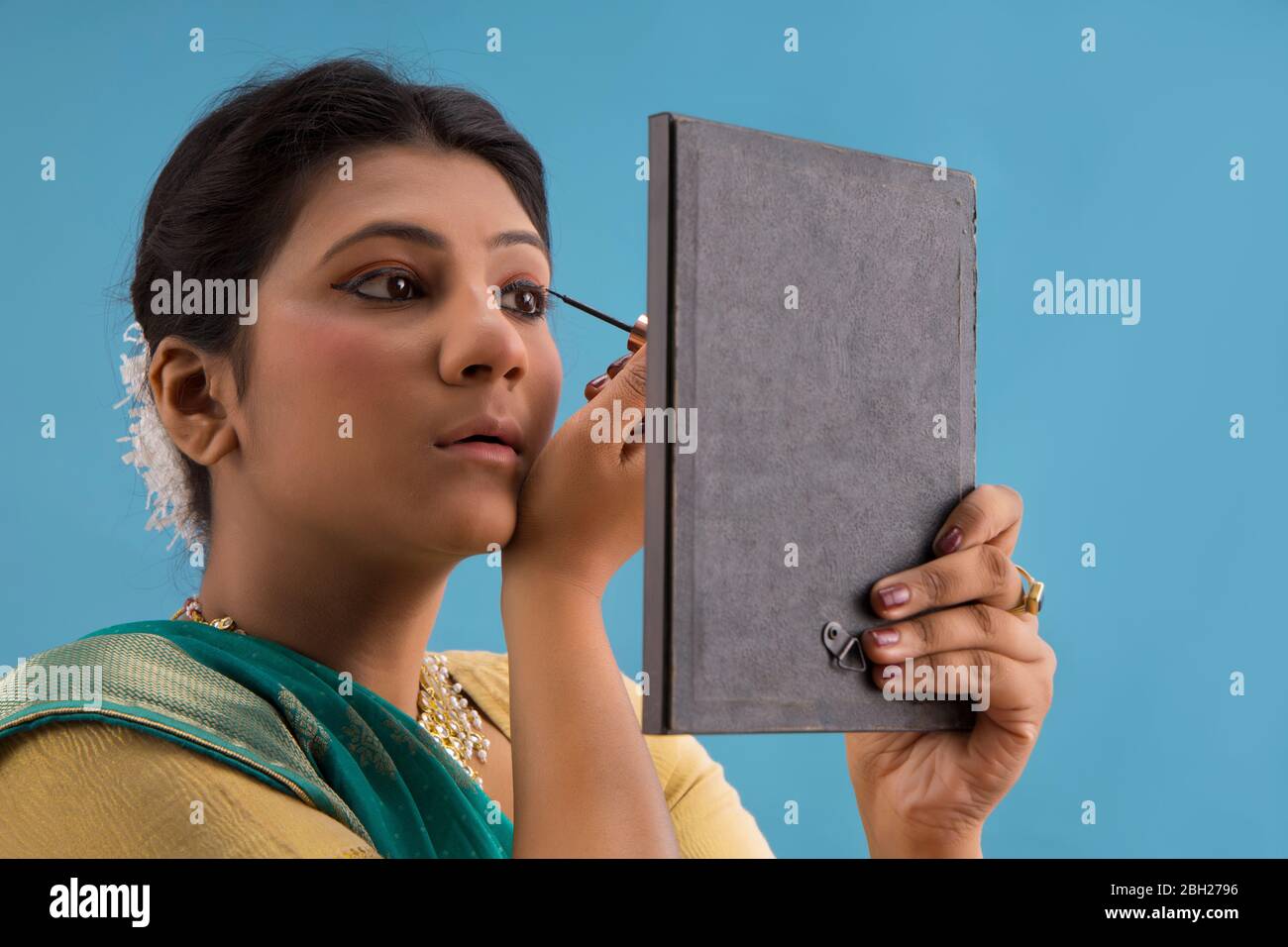 Kathak dancer applying eyeliner on her eyes. Stock Photo