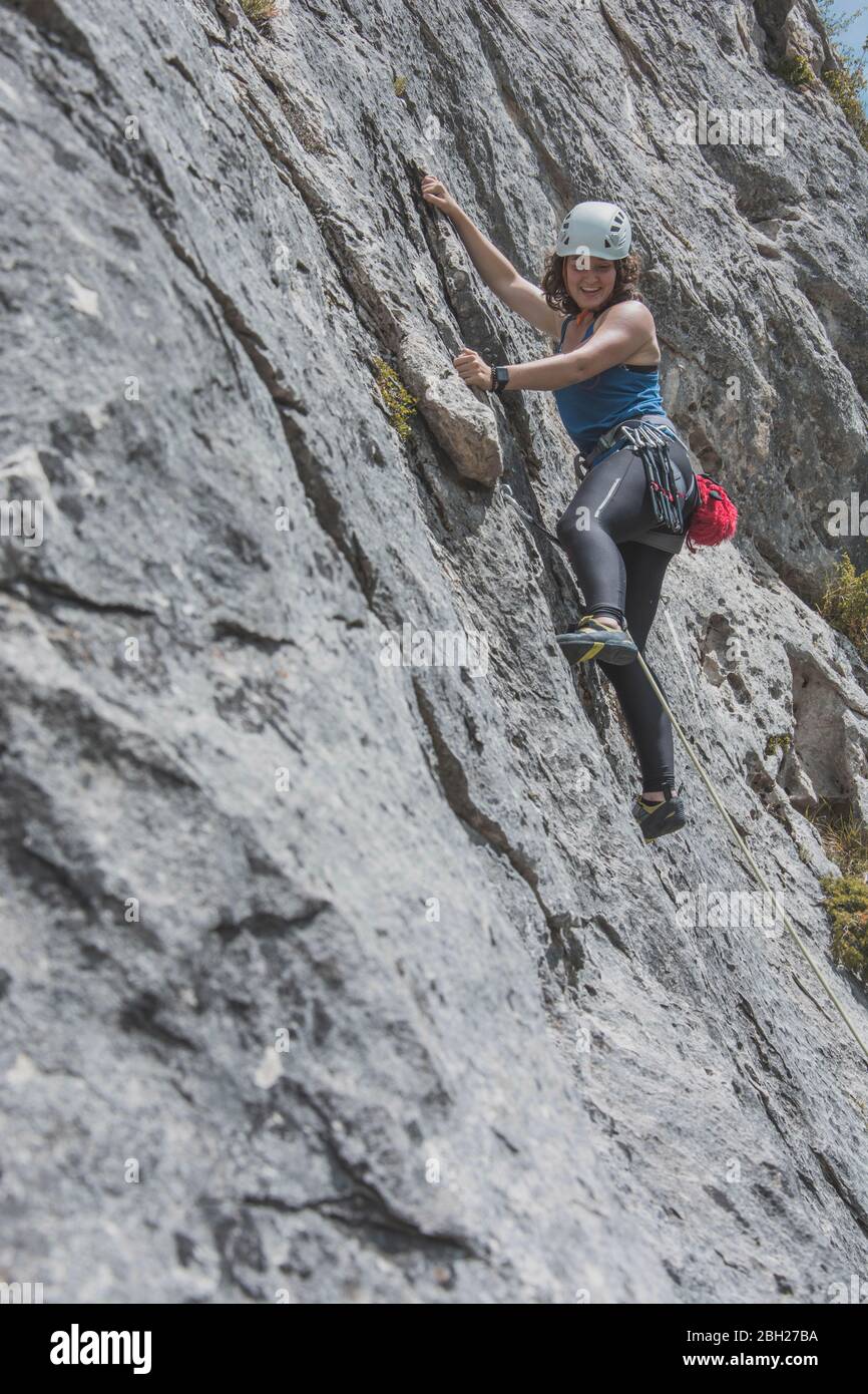 Female mountain climber climbing rock face Stock Photo