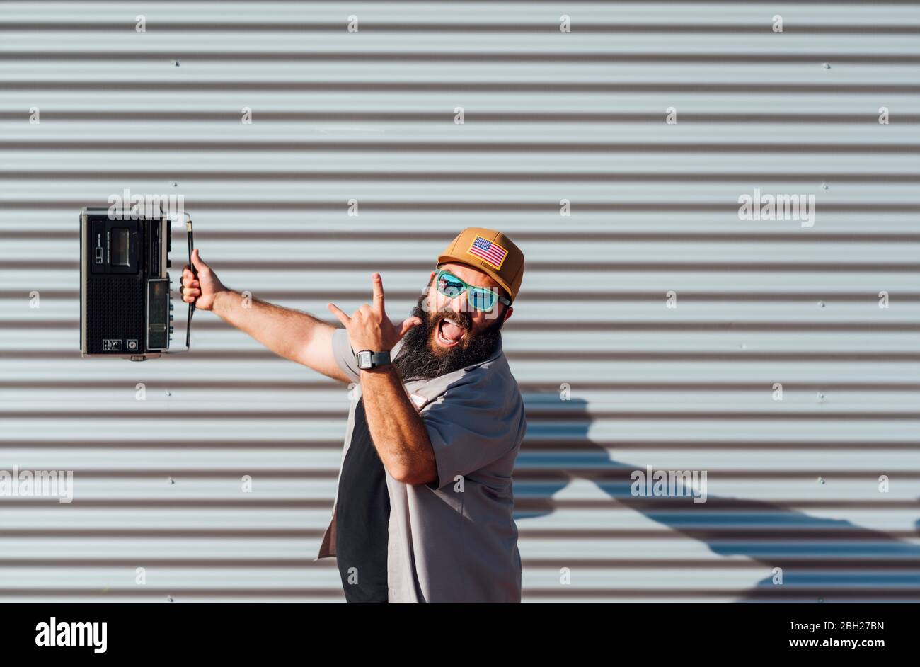 Portrait of bearded man with portable radio screaming and showing Rock And Roll Sign Stock Photo