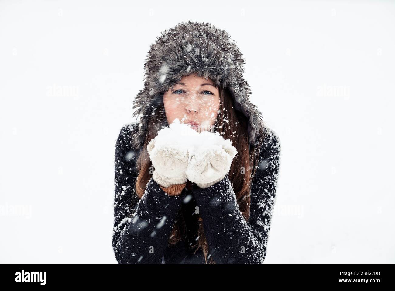 Portrait of young woman blowing snow Stock Photo