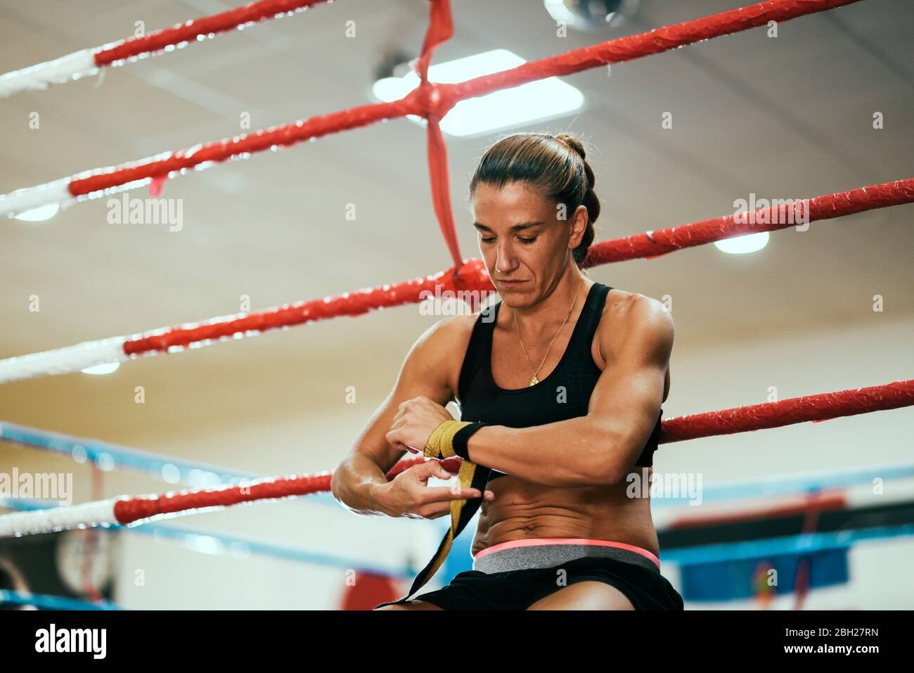 Woman tying bandage around her hand in boxing ring Stock Photo