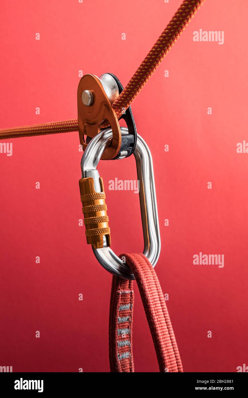 Climbing carabiner on harness loop and rope through pulley Stock Photo