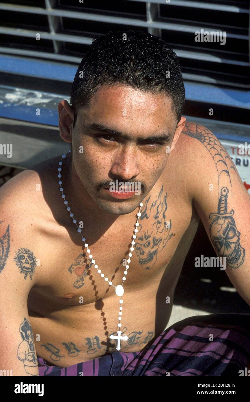Los Encinos Texas USA: Hispanic male gang member showing tattoos and rosary  beads at the beach