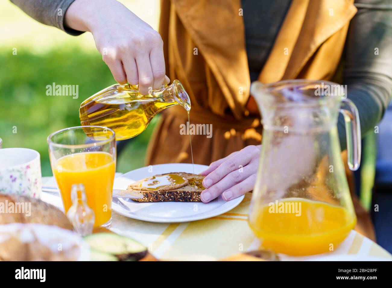 Close-up og woman pouring olive oil on bread Stock Photo