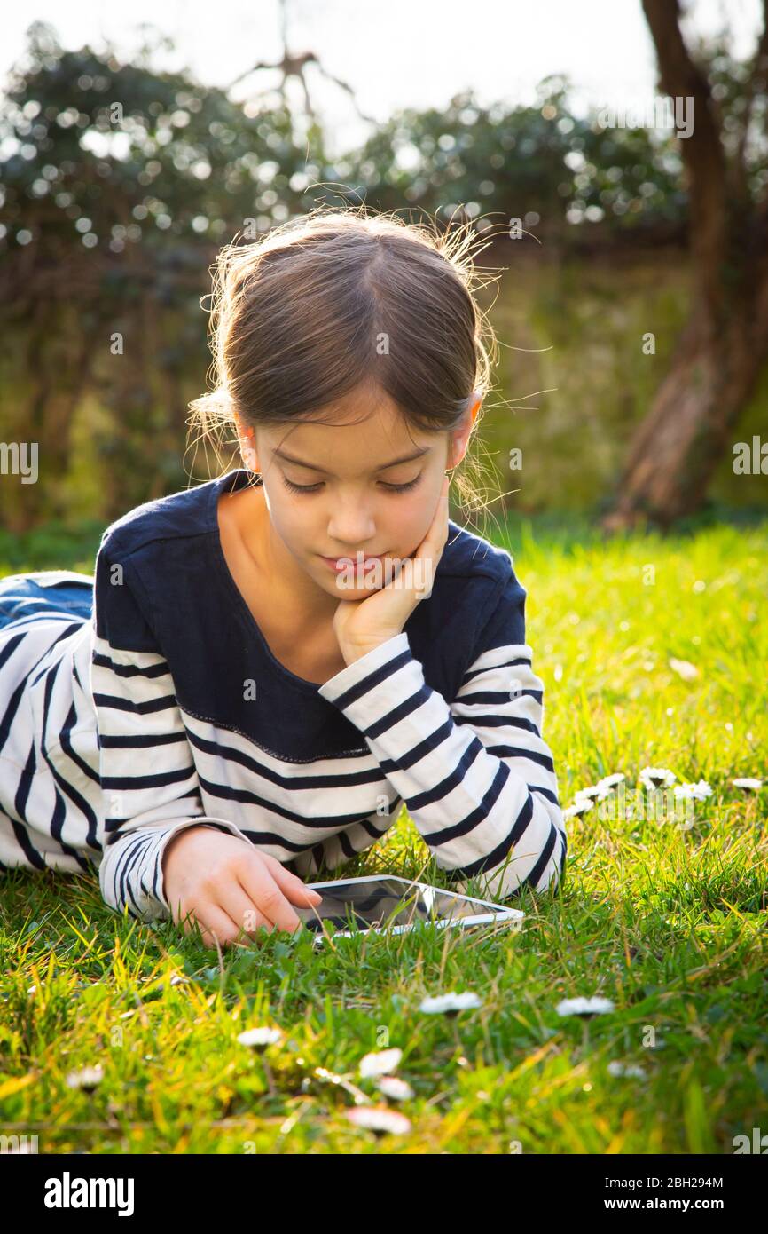 Portrait of little girl lying on a meadow using digital tablet Stock ...