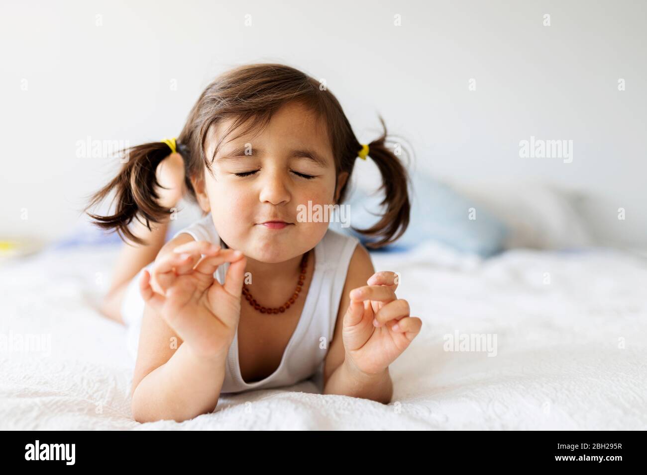 Portrait of little girl with eyes closed lying on bed at home Stock