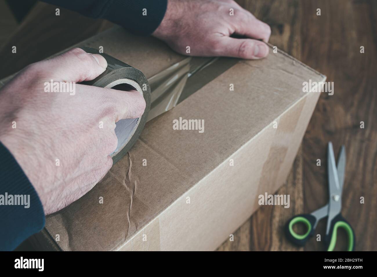 close-up of person sealing up shipping box with parcel tape, pruchase return and return of goods concept Stock Photo