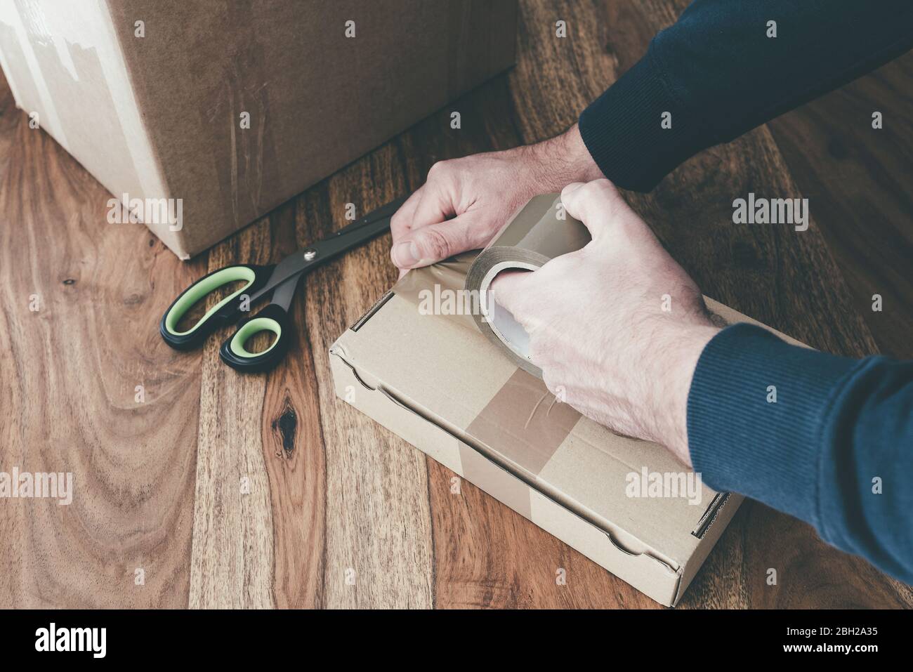 close-up of person sealing up shipping box with parcel tape, pruchase return and return of goods concept Stock Photo