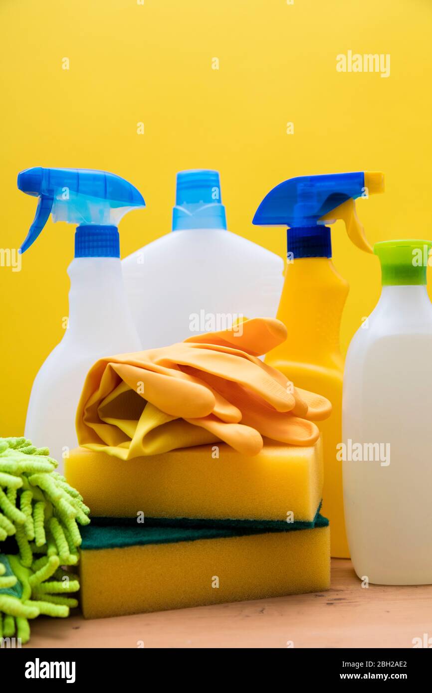 Cleaning spray bottles and cloths against a bright yellow background Stock Photo